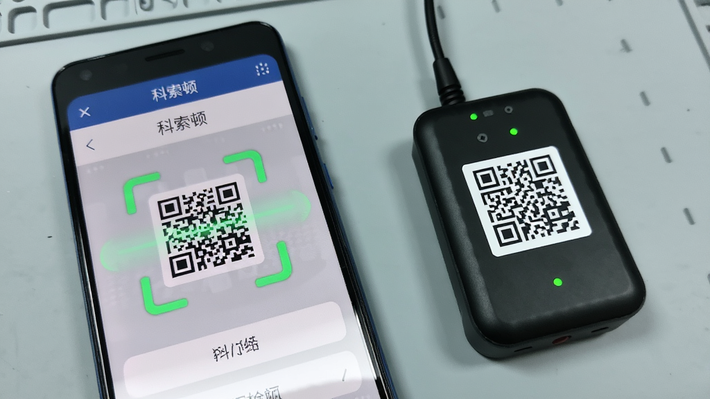 一部安卓手机屏幕显示科索顿App的设备绑定界面,画面中有扫描二维码的动画效果,手机旁边放着一台随身WiFi设备,设备背面二维码清晰可见,背景为淡灰色工作台面,风格写实简约,细节包括手机界面上的“科索顿”文字标识、绿色扫描框、设备指示灯,画质干净清晰,无多余装饰