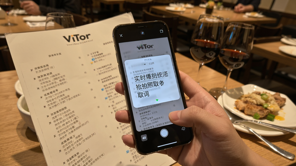 一幅展示ViiTor实时翻译拍照取词功能的画面,一只手拿着手机对准一份外文菜单,手机屏幕上显示翻译后的中文浮层,背景是餐厅环境,风格生活化,细节丰富,画质清晰,画面干净整洁