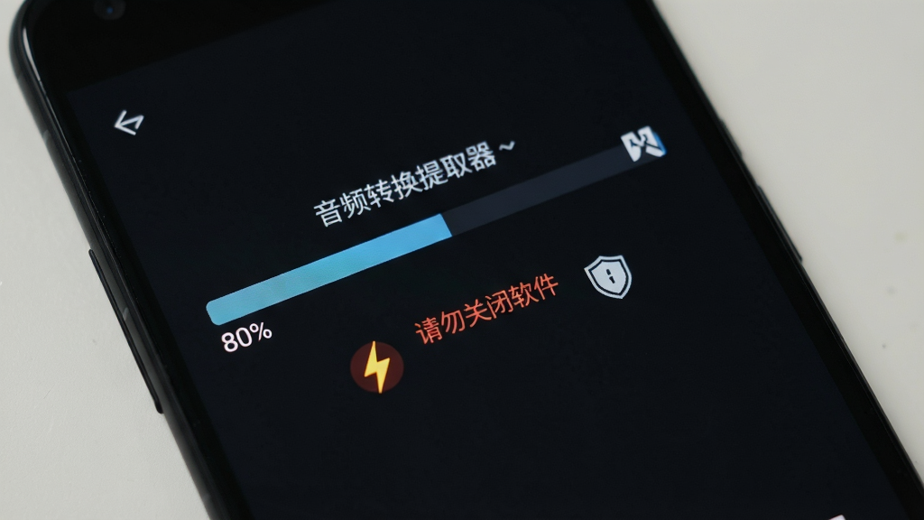 一部安卓手机显示音频转换提取器的转换进度界面,进度条显示80%,下方有“请勿关闭软件”的红色提示文字,旁边有闪电和盾牌图标,背景为深色护眼模式,画质清晰,无多余元素