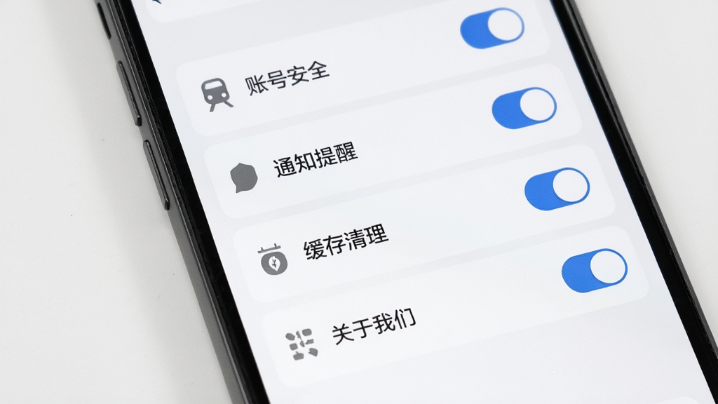 主体为手机屏幕显示火车票购票出行应用设置页面,布局为纵向列表排版,包含账号安全、通知提醒、缓存清理、关于我们等选项,风格为极简浅色风,细节包含灰色图标、白色背景、蓝色开关按钮,画质高清,干净,无多余元素