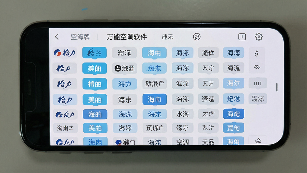 一张展示万能空调遥控软件内部界面的图片,画面中手机屏幕显示着密密麻麻的空调品牌列表,有格力、美的、海尔等标签,背景是简洁的浅色UI,风格为扁平化设计,细节清晰,画质干净,无多余元素