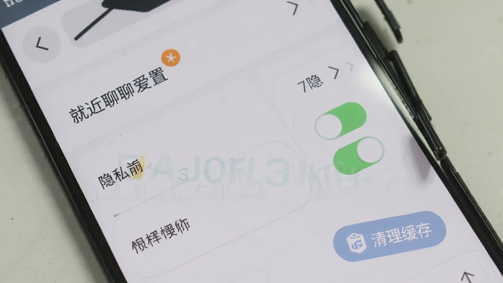 一部安卓手机显示就近聊聊爱设置页面,隐私选项和权限开关清晰可见,旁边有清理缓存按钮,界面简洁,画质干净,无多余元素