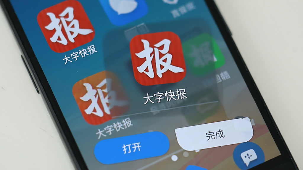 一部安卓手机展示大字快报的安装完成界面,屏幕上有