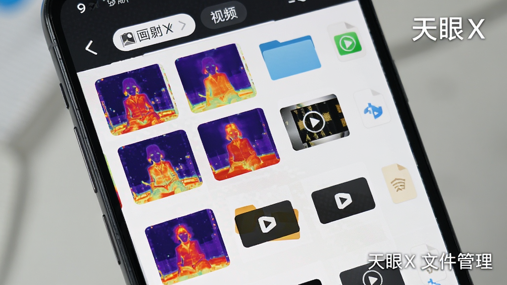 手机屏幕显示天眼X的文件管理界面,界面上排列着多张热成像缩略图与视频文件图标,顶部有相册和视频分类标签,布局为手机竖屏展示,风格为应用界面截图,细节包括缩略图色彩丰富、图标简约、间距舒适,画质高清,干净,无多余元素,图片中打文字“天眼X文件管理”