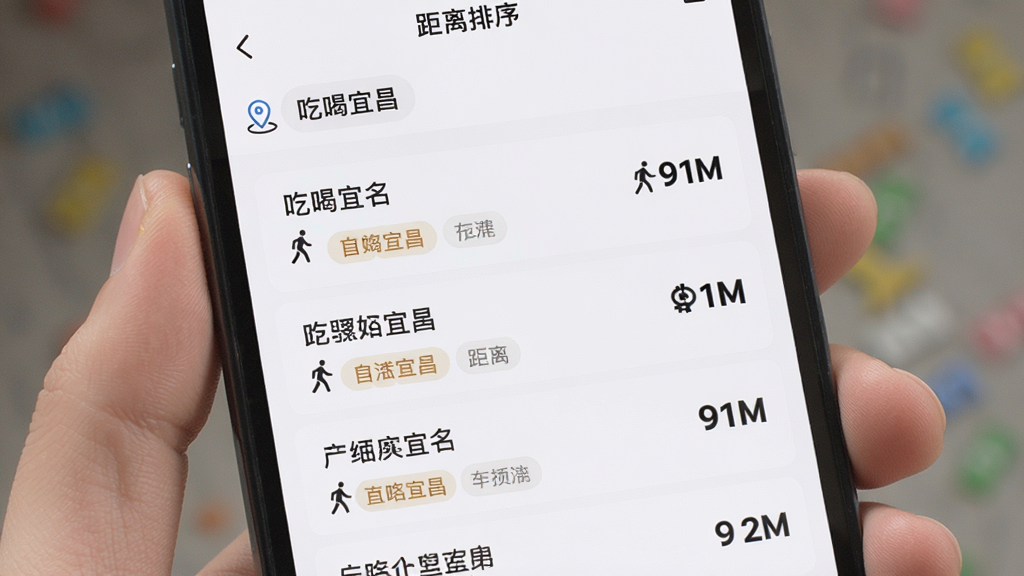 画面主体为手机屏幕内展示「吃喝宜昌」距离排序列表页面,布局为顶部定位条、中部按距离由近到远排列的商户条目,每条含店名、距离数字、标签,排版纵向单列清晰,风格为明亮浅色系移动端界面,细节包含定位图标、步行小人图标、距离数字加粗显示,画质高清,画面干净无多余元素