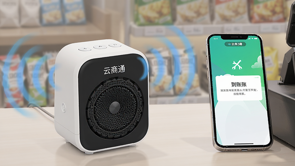 主体为一只放置在收银台上的小型语音播报音箱,布局为音箱居左、手机居右,排版横向排列,风格为写实产品摄影感插画,细节包括音箱发出的声波图形与屏幕上的到账提示,画质清晰干净,画面中文字为