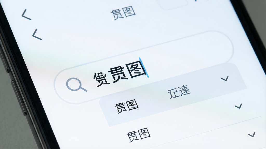 主体为手机界面特写,布局为搜索框居中放大展示,排版突出关键词输入区域,风格为清爽浅色系界面设计,细节包括搜索图标与联想词下拉列表,画质高清干净,无杂乱元素,画面中呈现“贯图”字样