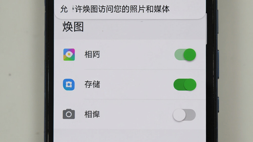 一部安卓手机屏幕显示“焕图”应用的权限设置页面,页面中列出相册、存储、相机三项权限开关,其中相册与存储权限处于开启状态,相机权限处于关闭状态,屏幕上方有系统提示条文字“允许焕图访问您的照片和媒体”;布局为手机界面居中展示,背景为浅灰色;风格为手机系统设置界面实拍风;细节上开关按钮带有绿色高亮,权限图标清晰;画质干净,无多余元素</p>