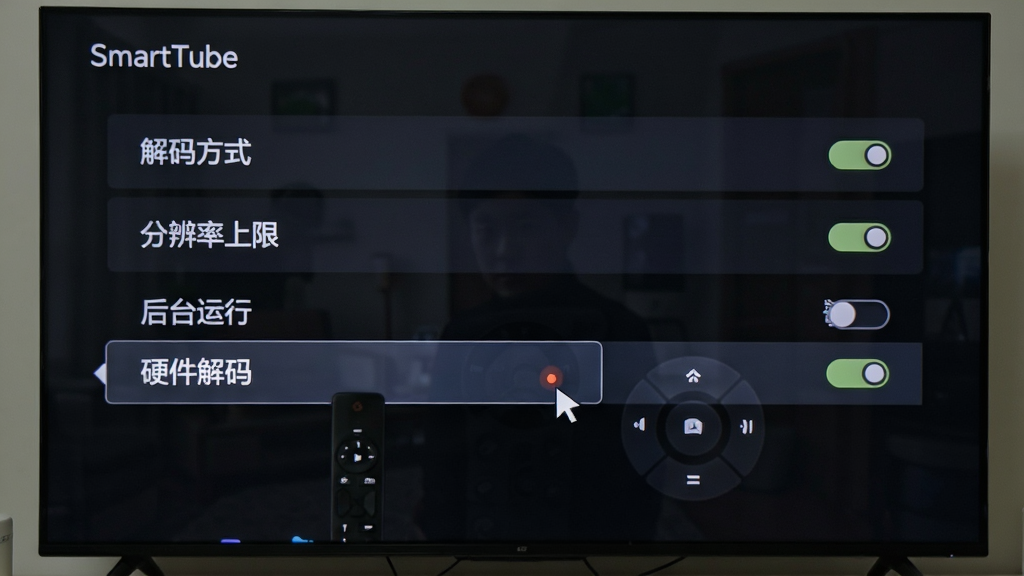电视屏幕显示SmartTube设置界面,包含解码方式、分辨率上限、后台运行开关等选项,画面中有遥控器光标高亮“硬件解码”,布局为列表式菜单,风格为深色系统界面,细节包含开关按钮、选项文字,画质清晰、干净无多余元素