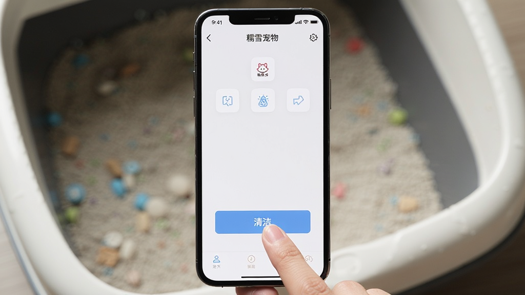 一部智能手机竖屏显示“糯雪宠物”操作界面,手指正点击“清洁”按钮,背景是模糊的猫砂盆,主体是手机屏幕,布局居中,风格写实,细节有按钮图标,画质清晰,干净无多余元素