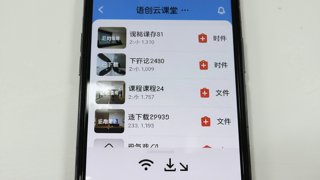 画面主体为手机屏幕特写,屏幕中显示语创云课堂的离线缓存管理页面,列表中包含多个已下载课程,每个课程右侧有删除按钮与文件大小标注。手机下方有WiFi信号图标与下载箭头图标。布局采用居中构图,风格简洁实用,细节上屏幕反光自然。画质清晰,背景干净,无多余元素。