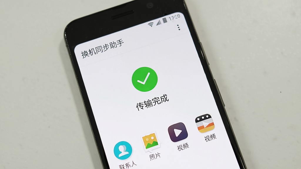 一部安卓手机显示换机同步助手传输完成界面,屏幕上有绿色对勾和“传输完成”字样,旁边有联系人、照片、视频等图标,背景为白色简洁风格,画质清晰,主体为手机屏幕和完成提示,画面干净,无多余元素,手机屏幕显示“换机同步助手”
