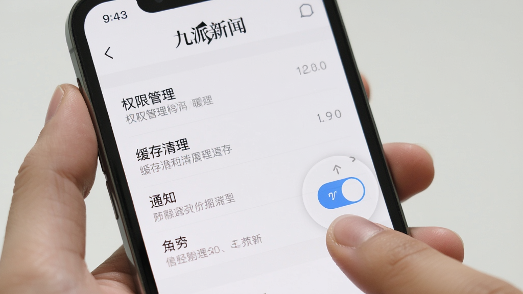 主体为手机屏幕显示“九派新闻”APP的设置页面,布局包含权限管理、缓存清理、通知开关等选项,排版采用列表式设计,风格简洁明了,细节有手指点击清除缓存按钮的动作,画质高清,干净,无多余元素