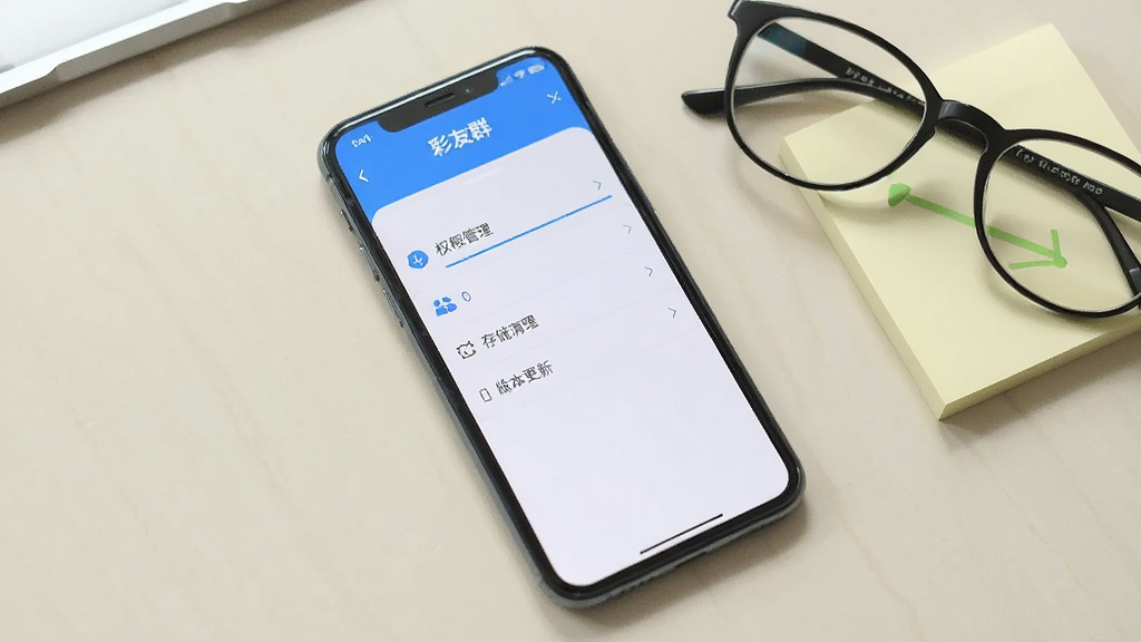 一部手机屏幕显示彩友群应用的设置页面,页面中有权限管理、存储清理和版本更新选项,背景为浅色桌面,手机旁边有眼镜和便签纸,风格简约实用,画质清晰干净,无多余元素