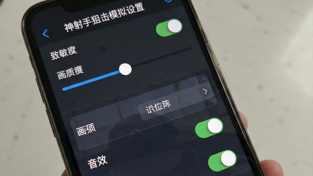 一张手机屏幕展示游戏设置界面的画面,画面中有灵敏度滑块、画质选项、音效开关等设置项。主体为手机设置界面,布局为竖版列表排列,排版清晰,风格为简洁UI设计,细节包括滑块图标、开关按钮、文字标签,画质高清、干净、无多余元素,画面中文字“神射手狙击模拟设置”。