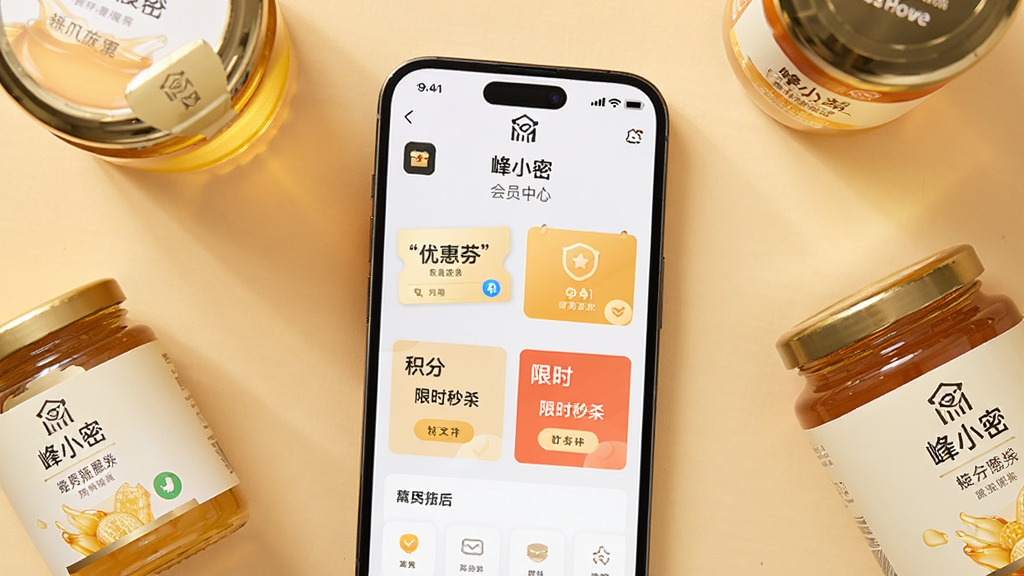 一部智能手机屏幕中展示“峰小密”APP的会员中心页面,页面内有优惠券、积分与限时秒杀板块,手机周围散落着几瓶不同规格的蜂蜜产品,背景为柔和的暖色调,布局采用俯视平铺构图,风格为现代简约,细节包括手机界面的图标与文字、蜂蜜瓶的标签,画质清晰,画面干净无杂乱元素