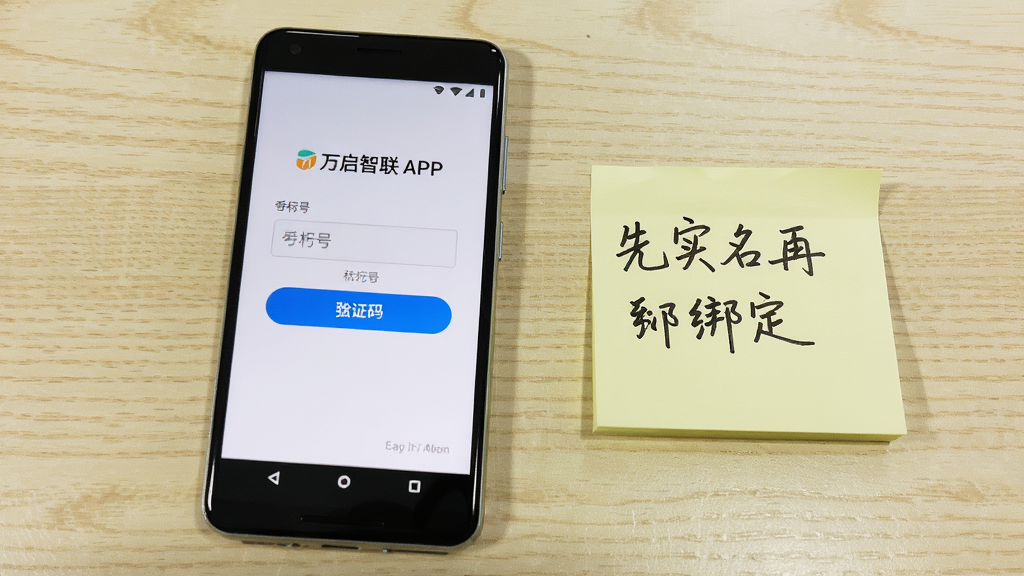 一部安卓手机放置在桌面上,屏幕显示万启智联APP的登录页面,页面中有手机号输入框和验证码按钮,手机旁边有一张手写便签写着“先实名再绑定”,背景为浅色木纹桌面,整体风格为教程指引风,细节包括便签字迹清晰、屏幕界面简洁,画质清晰干净,无多余元素。