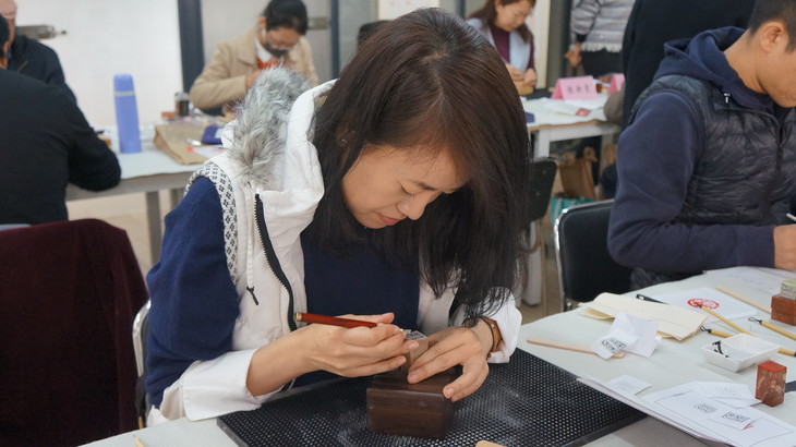 篆刻教师手把手教零基础学员刻印章的场景