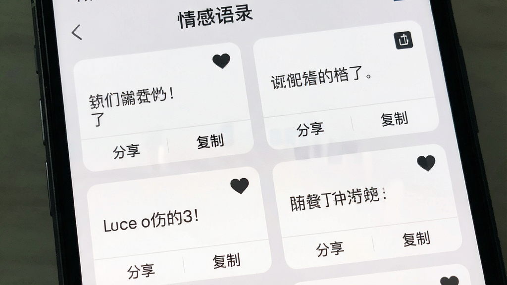 手机屏幕展示“情感语录”的收藏夹页面,页面中排列着多条已收藏的语录卡片,每张卡片右上角有一个实心爱心图标,底部有“分享”和“复制”按钮,背景为浅灰色,卡片为白色,文字为深灰色,整体布局为双列网格,风格简洁,画质清晰,画面干净,无多余元素