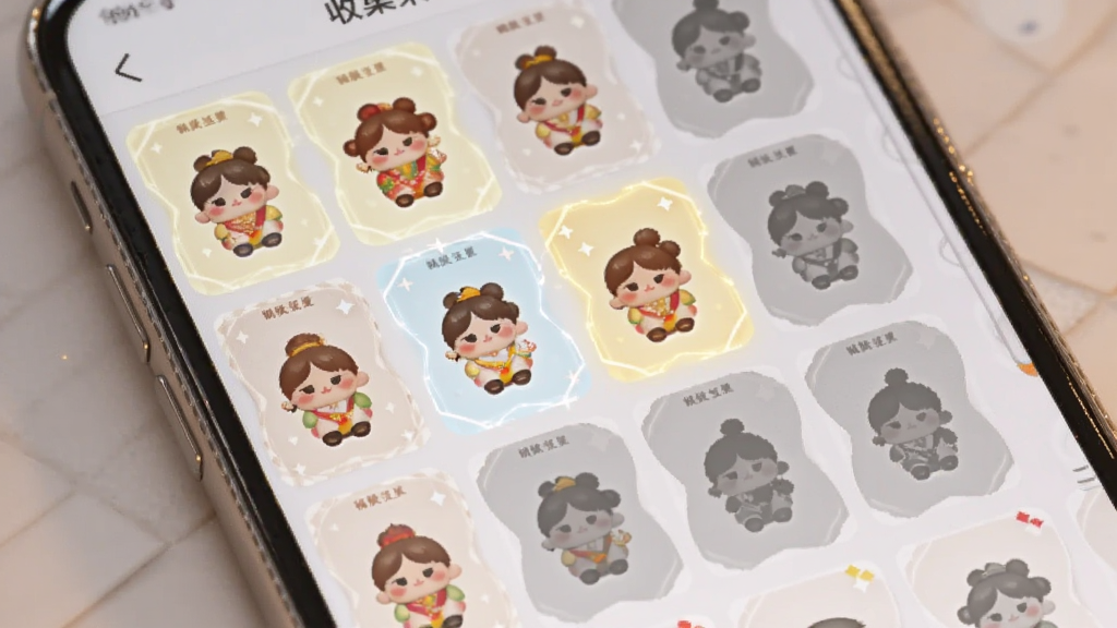 画面展示一个手机屏幕,屏幕上是一个收集册界面,里面排列着各种不同造型的福运娃娃和卡片,有些已经点亮,有些还是灰色剪影。布局为平铺展示,排版整齐。风格为清新治愈系,色调柔和。细节上,点亮的卡片有微弱的发光效果。画质高清,干净,无多余元素。