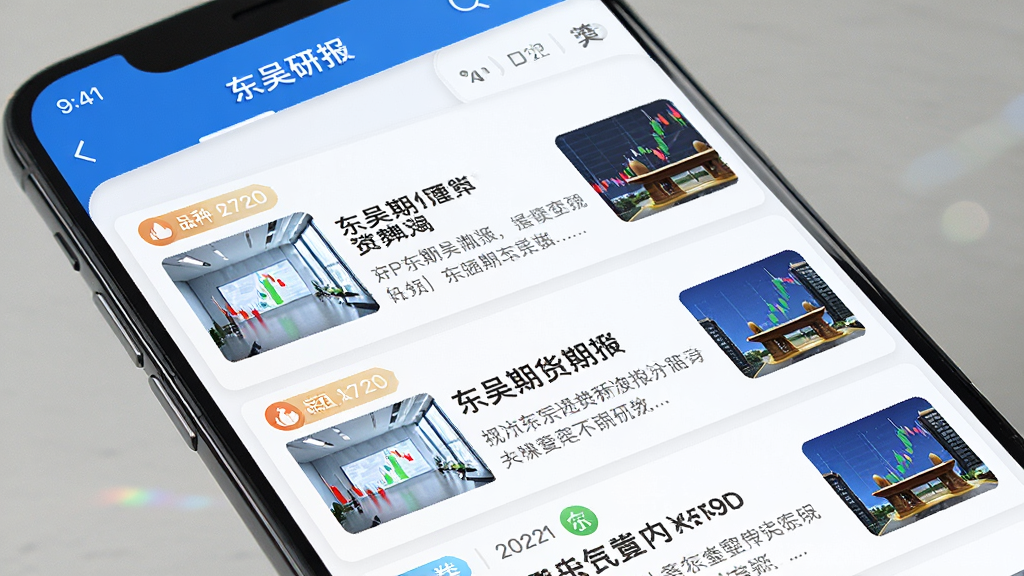 手机屏幕上展示东吴期货通APP的资讯研报列表页面,主体为一部智能手机,屏幕内显示多条期货资讯标题与摘要卡片,布局为纵向列表排列,风格为清爽阅读界面,细节包含日期标签、品种分类图标、缩略图,画质清晰干净无多余元素