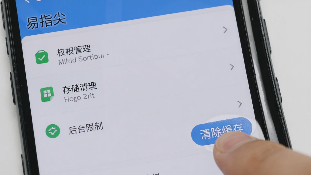 一部安卓手机屏幕显示“易指尖”的设置界面,界面中列出了权限管理、存储清理、后台限制等选项,旁边有手指正在点击“清除缓存”按钮。画面背景为浅灰色,手机边框清晰,界面文字可辨,整体风格实用简洁,画质高清,无多余元素。