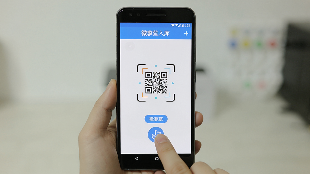 微掌柜新手操作手机界面展示图,主体为一部安卓手机显示微掌柜扫码入库界面,布局为居中手机正面视角,风格为清晰教程风,细节包括手指点击扫码按钮的动作和屏幕上的对焦框,画质清晰,干净,无多余元素