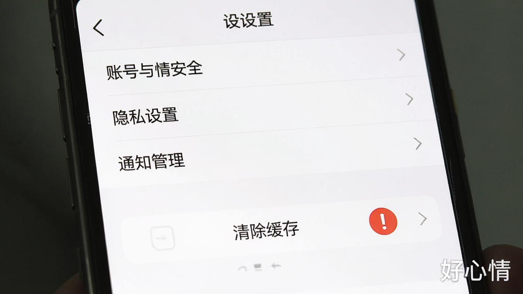 一张手机屏幕截图风格的图片,画面中显示好心情APP的“设置”页面,页面顶部有“账号与安全”“隐私设置”“通知管理”等选项,下方有“清除缓存”按钮,按钮旁边有一个红色感叹号图标,整体布局清晰,风格简洁,画质高清,干净无多余元素,图片右下角有“好心情”水印。