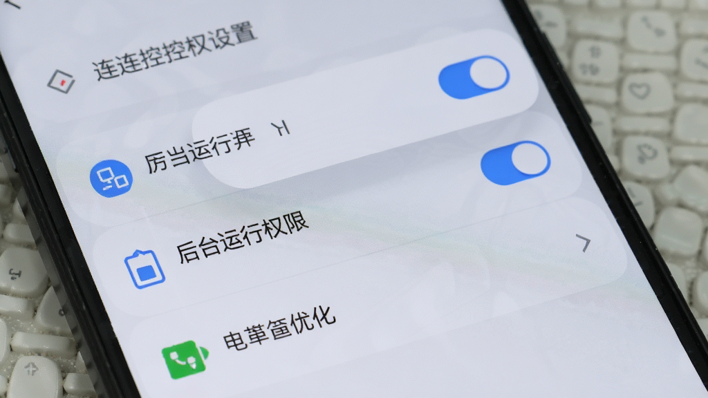 手机屏幕展示连连控权限设置页面,画面中有悬浮窗权限开关、后台运行权限开关和电池优化选项,背景为浅灰色,布局为列表形式,风格简洁实用,细节包括图标和文字标签,画质清晰,干净无多余元素