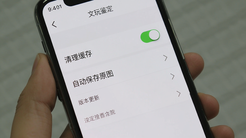 手机屏幕显示“文玩鉴定”的设置页面,页面中有“清理缓存”“自动保存原图”“版本更新”等选项,背景为浅灰色,布局为竖版手机界面,风格为简洁工具类UI,细节包含开关按钮、箭头图标、文字标签,画质清晰、画面干净、无多余元素