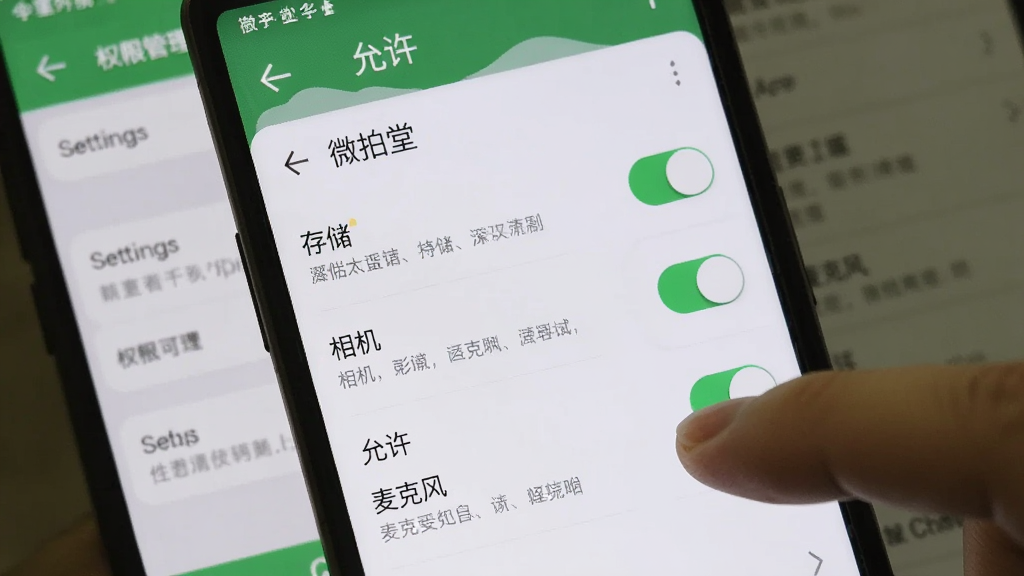 画面主体为一部安卓手机显示微拍堂APP的权限管理界面,屏幕上有“存储”“相机”“麦克风”等权限开关,旁边有一只手正在点击“允许”。背景是手机设置页面的模糊背景。布局为手机界面特写,风格为系统设置截图感,细节包括开关的绿色高亮、权限说明文字,画质清晰,干净,无多余元素