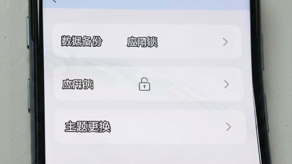 一张展示手机应用设置界面的图片,画面中有“数据备份”“应用锁”“主题更换”等选项按钮,界面风格简洁,背景为浅灰色,画质清晰,干净无多余元素