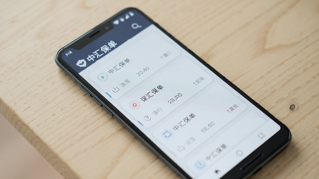一部安卓手机放置在浅色桌面上,屏幕显示中汇保单列表页面,多条保单卡片纵向排列,界面整洁,光线柔和,风格简约现代,画质清晰干净
